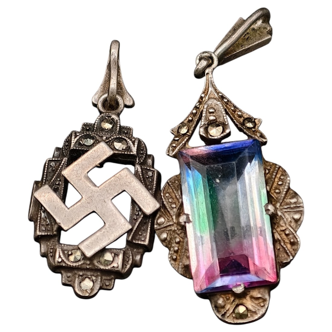 Third Reich Swastika Nazi Pendant Set 835 Silver: Two pendants in what appears to be silver of similar Art Deco marcasite design, one featuring an openwork swastika motif and the other set with a large faceted bi-color glass/crystal stone in blue,