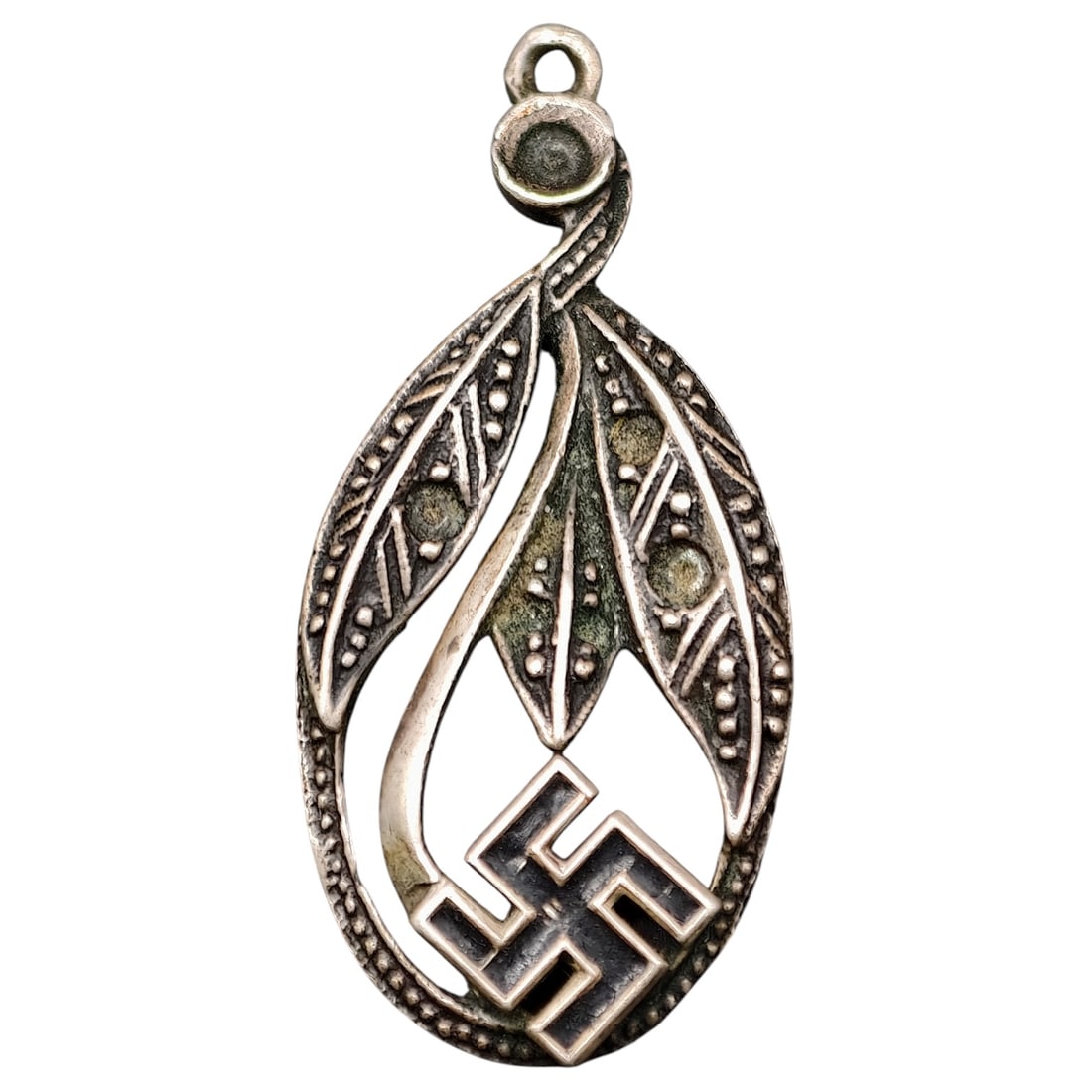 Third Reich Swastika Nazi Pendant: A small oval pendant featuring an openwork swastika design set beneath a stylized foliate motif with beaded and hatched decorative borders. The reverse is plain and undecorated, showing a rounded susp