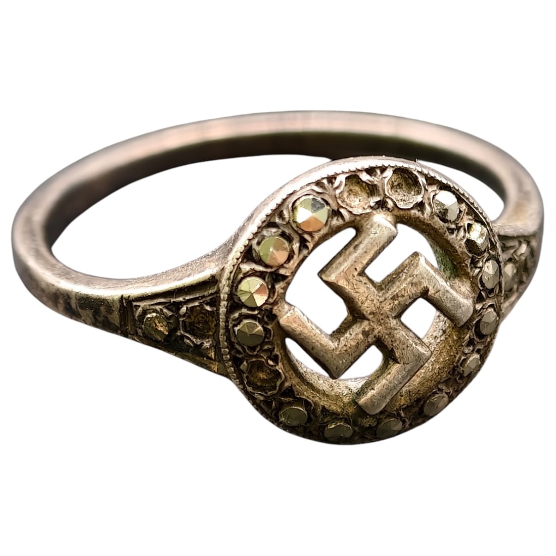 Third Reich NSDAP Nazi Sympathizer Ring: A ring in what appears to be silver featuring an oval bezel with a raised swastika at center, encircled by small faceted marcasite stones. The shoulders of the band also carry marcasite accents. No vi