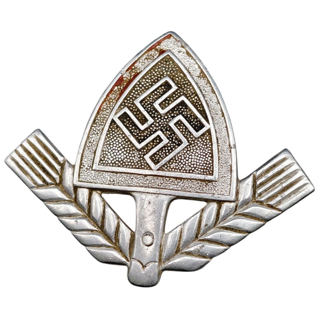 Third Reich Nazi RAD Cap Insignia: A cap insignia in what appears to be metal featuring a swastika within a shield-shaped surround, flanked by stylized wheat sheaves, worn by members of the Reichsarbeitsdienst (RAD). Front retains a fi