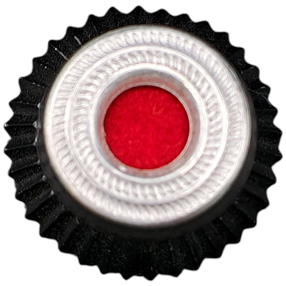 German Cockade-Style Rosette Badge with Red Center: A small round cockade/rosette badge featuring a serrated black outer edge, a fluted metal ring in what appears to be silver-tone, and a red felt or fabric center disc. The reverse shows faint die-stam