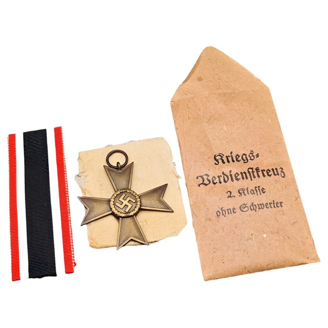 Third Reich Nazi War Merit Cross in Envelope: A Kriegsverdienstkreuz 2. Klasse ohne Schwerter (War Merit Cross 2nd Class without Swords), construction in what appears to be bronze-toned zinc with central roundel dated 1939 and swastika motif. Com