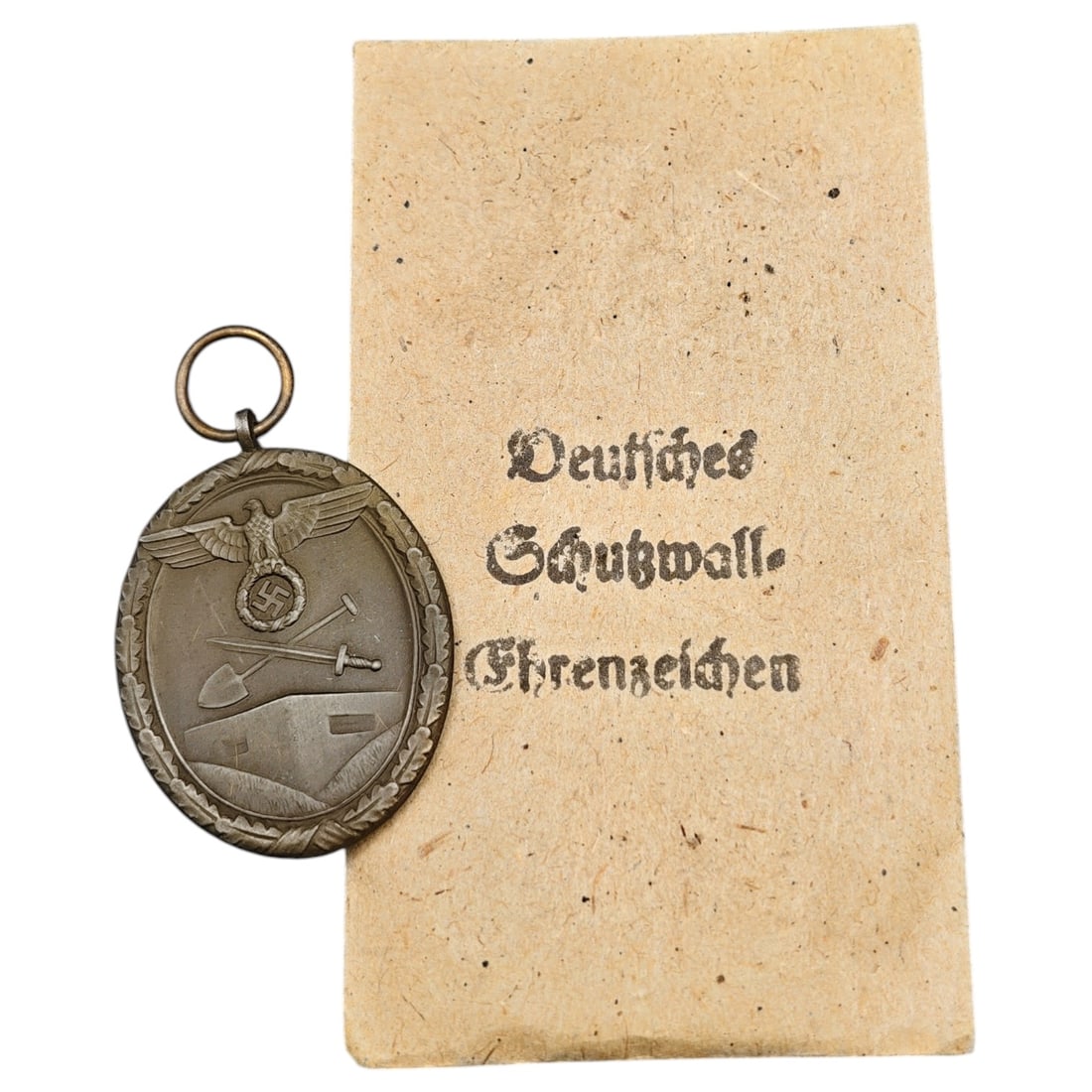 Third Reich Westwall Medal with Evelope: Deutsches Schutzwall-Ehrenzeichen (Westwall Medal), in what appears to be a bronze tone, depicting an eagle with swastika above a bunker with crossed spade and sword to obverse, reverse inscribed 'FÜ
