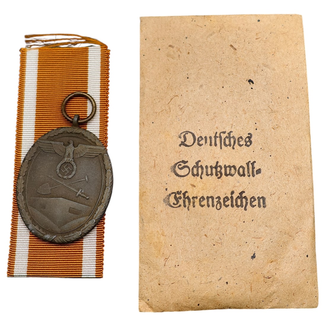 Third Reich Westwall Medal with Original Issue Envelope: A Westwall Medal (Schutzwall-Ehrenzeichen), awarded for work on the Siegfried Line fortifications, featuring an eagle and swastika above crossed sword and shovel on the obverse, with the reverse inscr