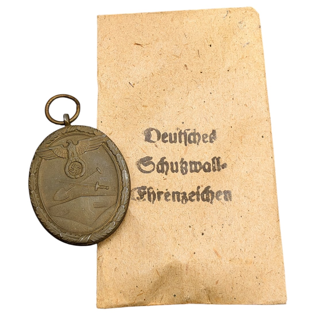 Third Reich Westwall Medal with Evelope: A Deutsches Schutzwall-Ehrenzeichen (Westwall Medal), bronze-toned, depicting an eagle with swastika above a crossed shovel and sword on the obverse, with reverse inscription 'FÜR ARBEIT ZUM SCHUTZE