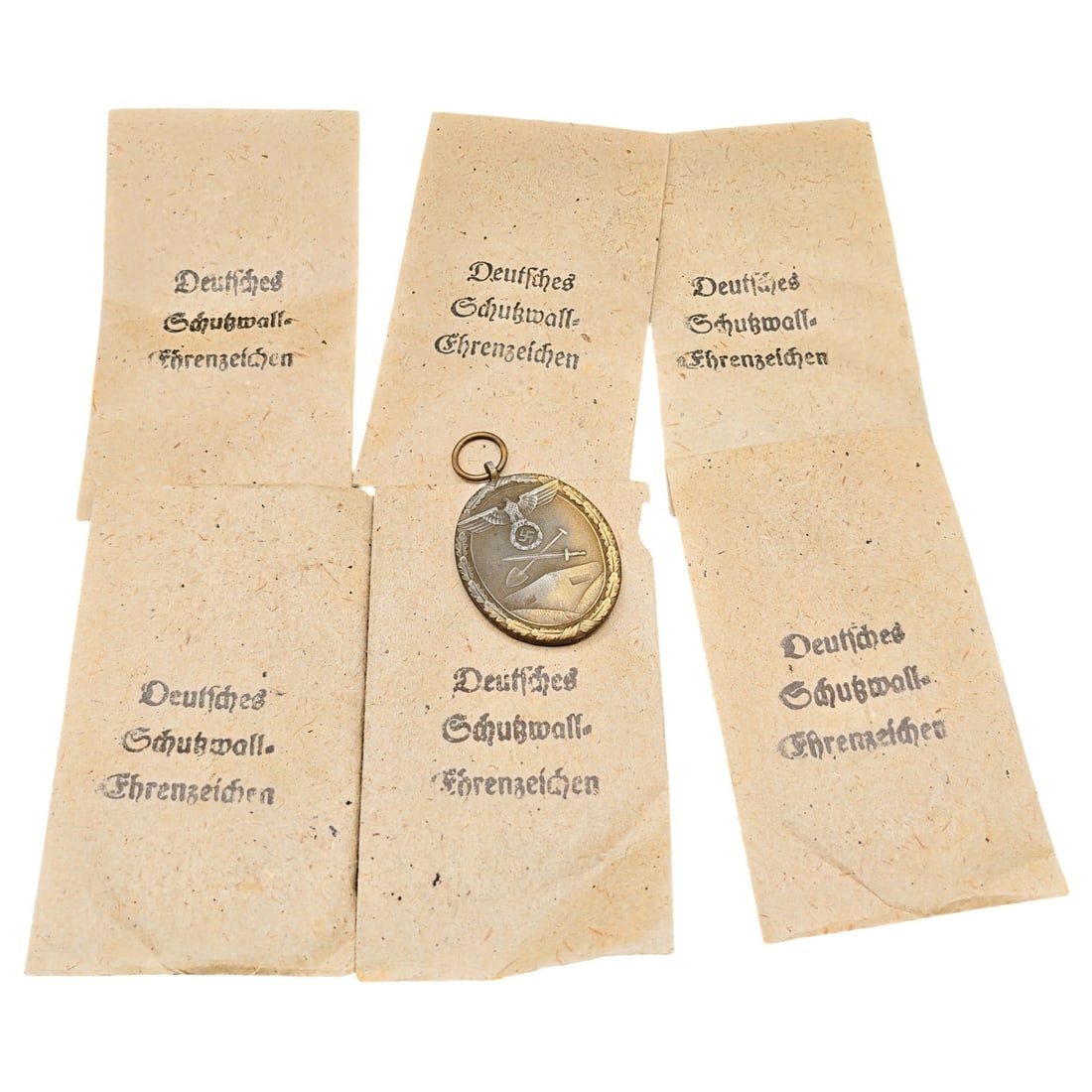 German WWII Schutzwall-Ehrenzeichen (Westwall Medal) with Original Packets of Issue: A set of West Wall Medals (Deutsches Schutzwall-Ehrenzeichen) displaying an eagle clutching a swastika over crossed sword and spade on the obverse, with the reverse inscription 'FÜR ARBEIT ZUM SCHUTZ