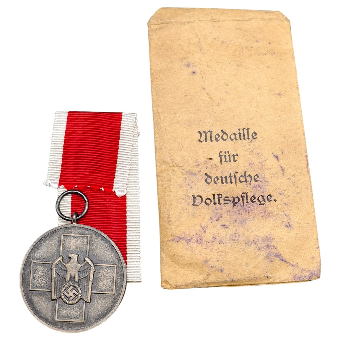 Third Reich Nazi Red Cross Service Medal with Envelope: A medal in what appears to be silvered zinc with eagle and DRK-style cross motif, obverse depicting an eagle atop a red cross flanked by swastika, reverse inscribed 'Medaille für deutsche Volkspflege