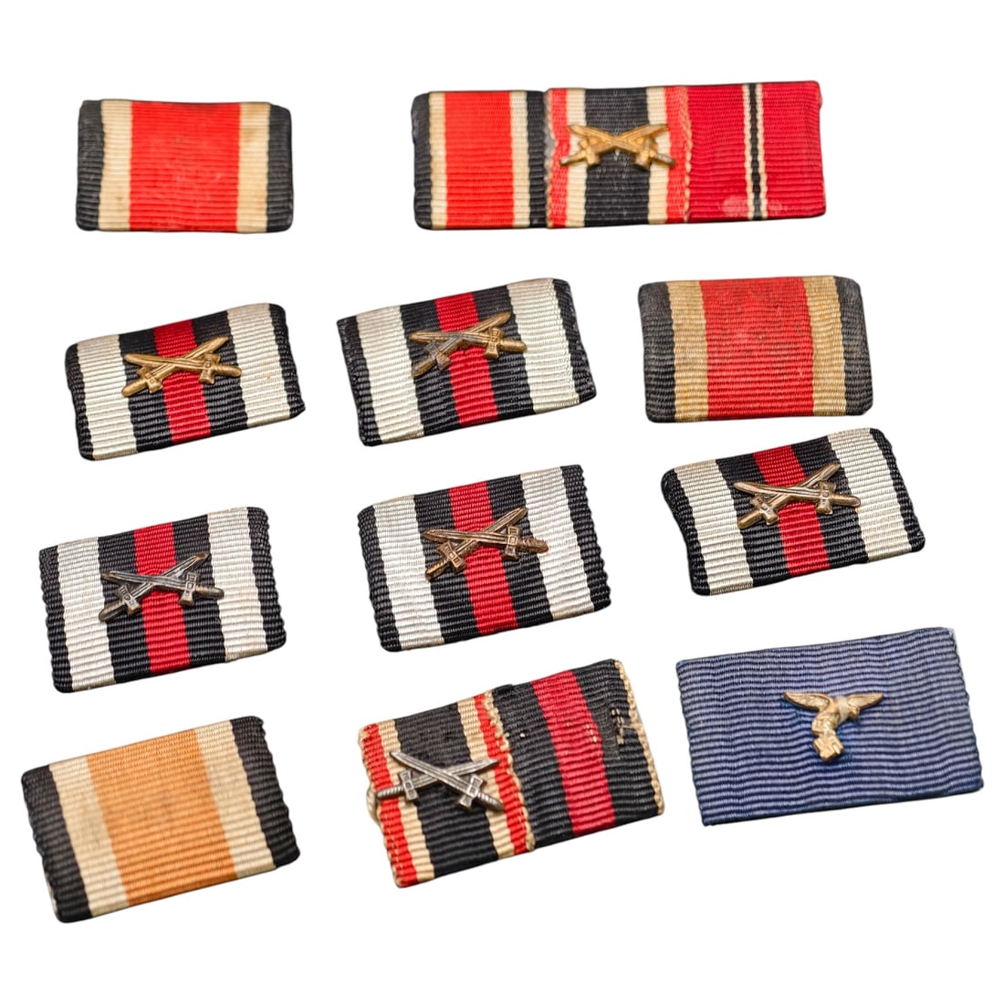 Third Reich Nazi Ribbon Bar Set: A lot of ribbon bars, primarily Iron Cross combat/service ribbons with applied crossed-swords devices denoting combatant awards, plus one blue-striped ribbon with an eagle device likely Luftwaffe rela