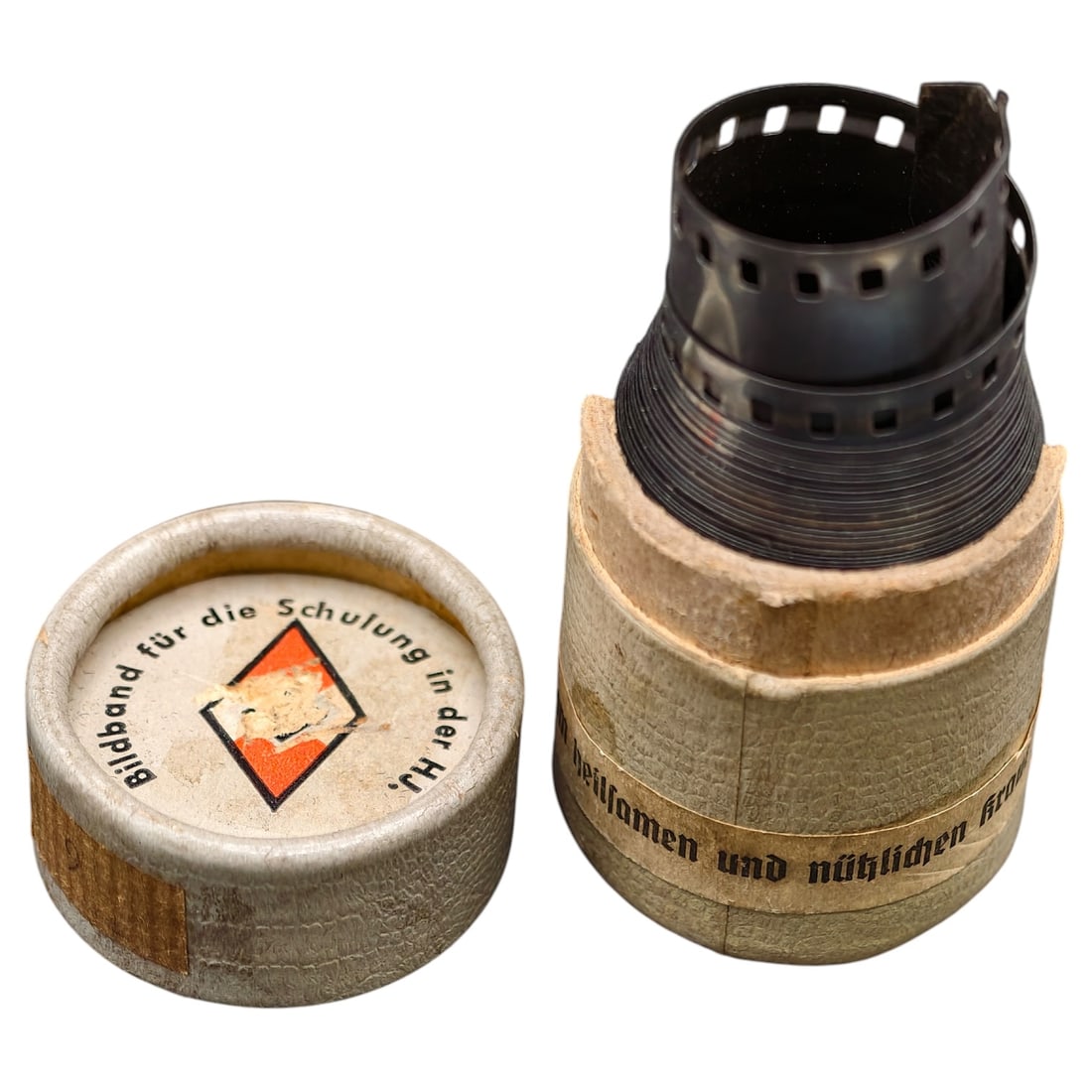 Hitler Youth Film in Canister: A cardboard canister with lid labeled "Bildband für die Schulung in der HJ" (Picture reel for training in the Hitler Youth), featuring the HJ diamond emblem printed on the lid. Contains a coiled 35mm