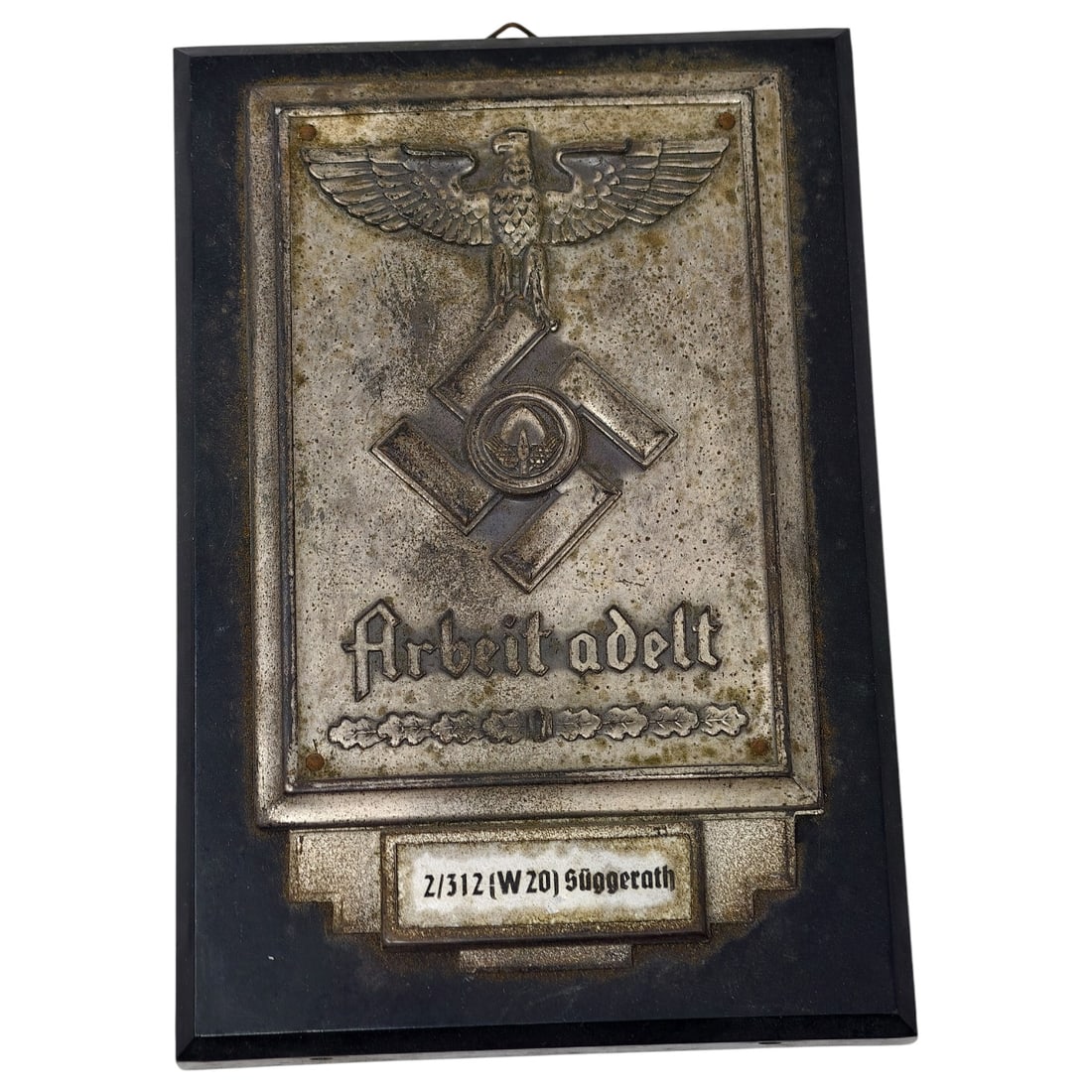 German WWII Reichsarbeitsdienst (RAD) 'Arbeit adelt' Wall Plaque: A pressed metal plaque, believed to be metal, mounted on a black-painted wooden backing board, featuring an eagle above a mobile swastika device and the motto 'Arbeit adelt' (Work ennobles), a slogan 