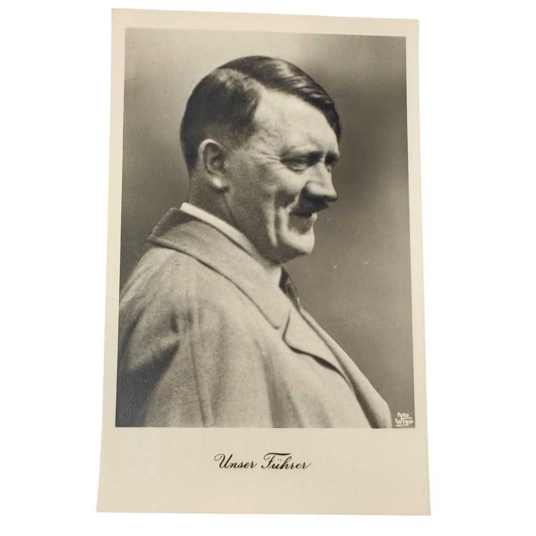 Adolf Hitler Postcard: Unused period postcard featuring a profile portrait photograph of Adolf Hitler, captioned "Unser Führer" in cursive script. The photo credit "Foto Wigo" appears in the lower right corner of the