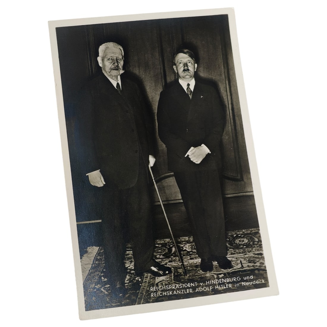 Adolf Hitler Postcard: Real-photo postcard depicting Reichspräsident von Hindenburg and Reichskanzler Adolf Hitler standing together at Neudeck, with printed caption at lower right identifying both men. Verso bears