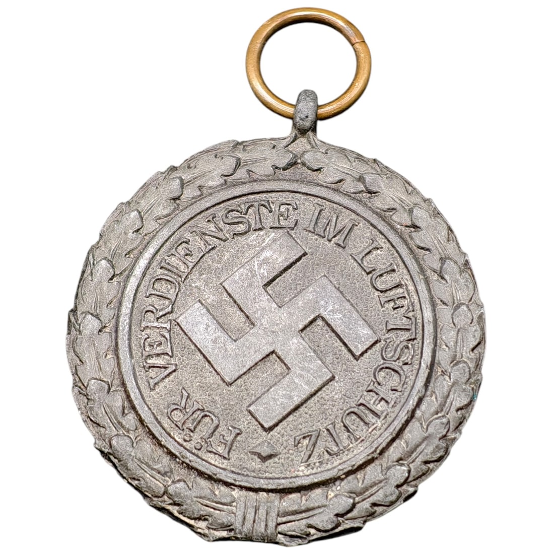 German WWII Luftschutz Medal 'Für Verdienste im Luftschutz' 1938: A Third Reich air defense (Luftschutz) merit medal in a light metal, believed to be zinc alloy, with a suspension ring. One face bears a swastika within an oak leaf wreath and the inscription "FÜR VE