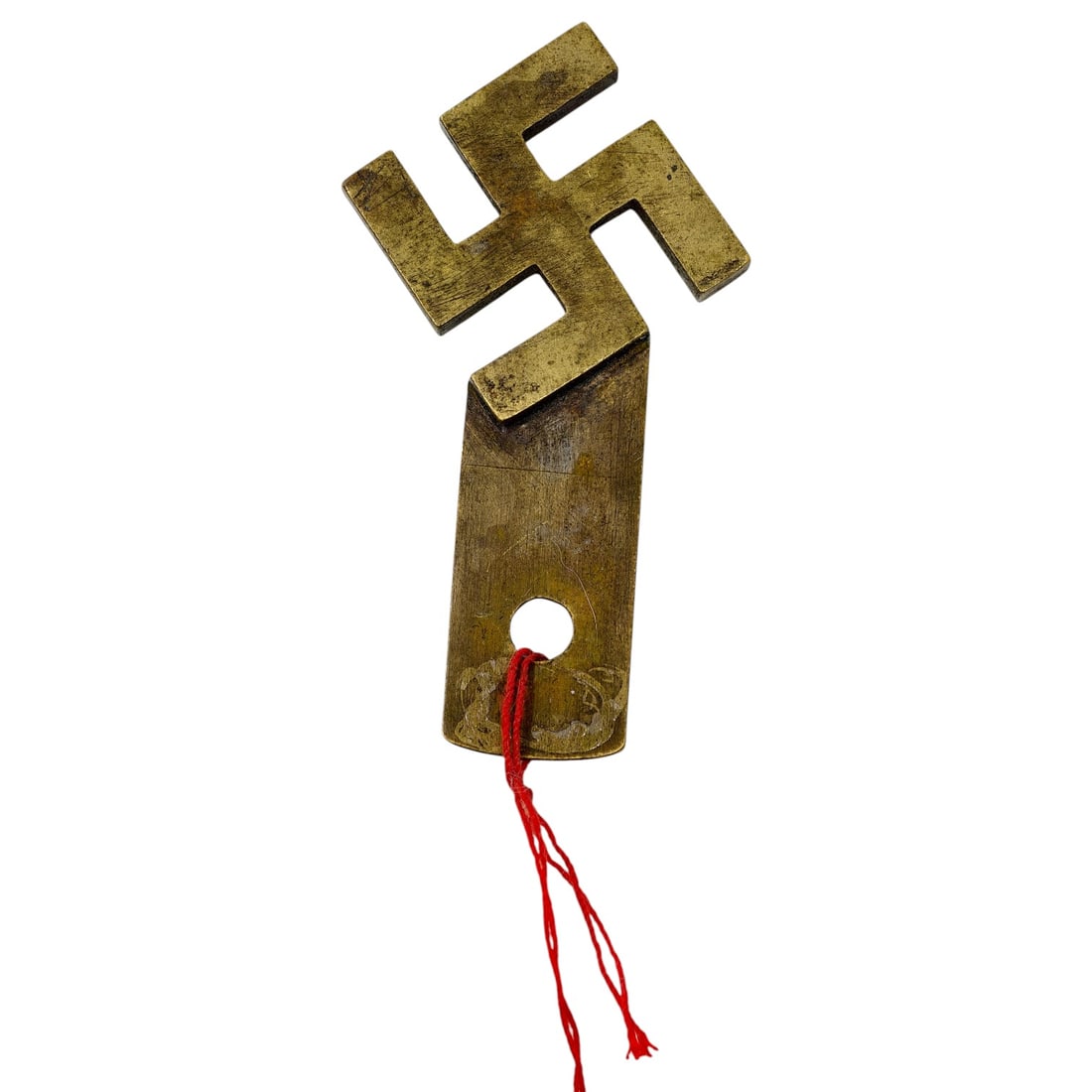German WWII-Era Metal Hakenkreuz Tag: A cast metal tag in the form of a hakenkreuz (swastika) with an integral rectangular tab pierced by a hole, believed to be brass. A length of red thread passes through the hole. The compact size and p