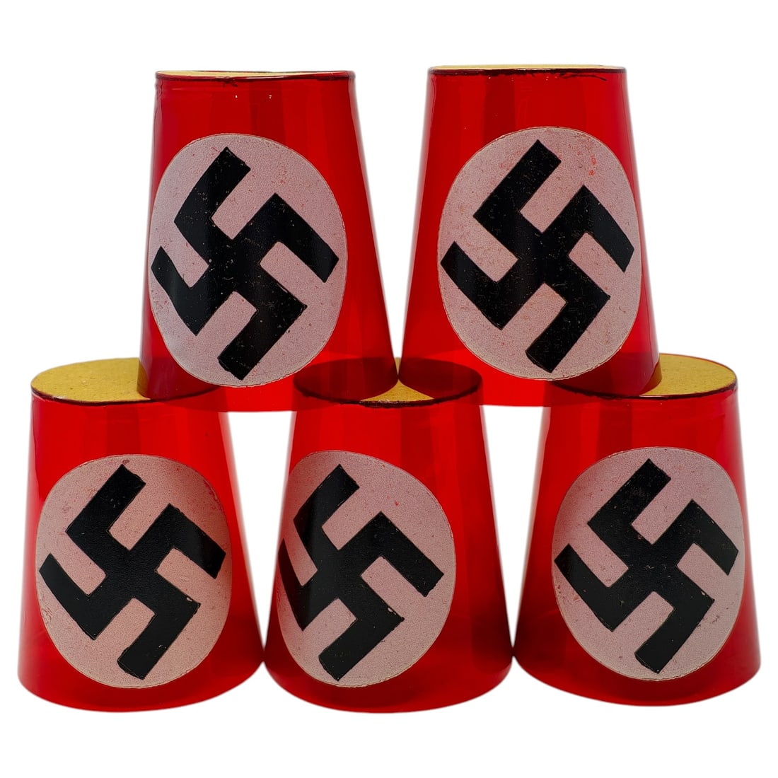 Set of Third Reich Red Candle Cups with NSDAP Emblem: A set of tapered, cone-shaped cups in translucent red, each decorated with a white circular field bearing a black swastika. The shades have a gilt-toned rim at the wider end and narrow toward the base