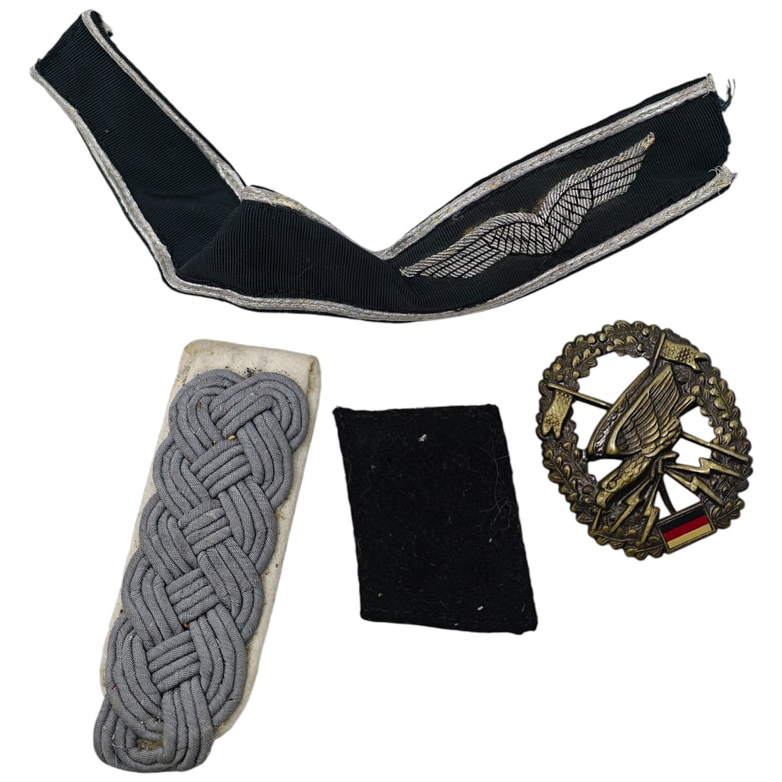 German Luftwaffe Officer's Insignia Group: German Insignia Group This lot includes a sleeve/collar wing insignia in silver-thread embroidery on dark cloth backing with a woven edge, a shoulder board in twisted cord on a cloth underlay, a plain