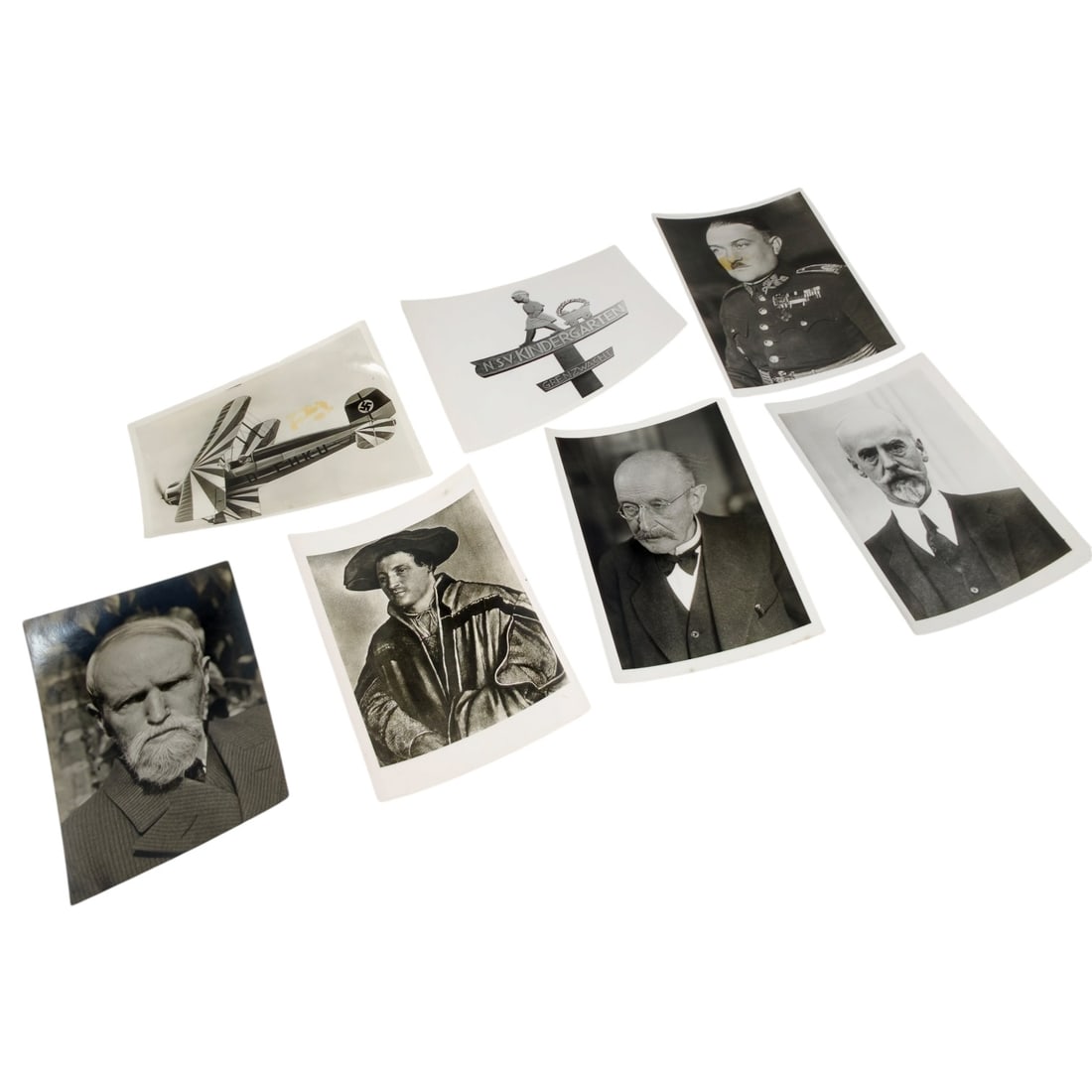 Set of German Third Reich Era Press Photographs: A set of period press photos including a portrait of a decorated military officer, a biplane aircraft marked with a swastika tail insignia and civil registration "D-EHKU," a NSV Kindergarten donation 