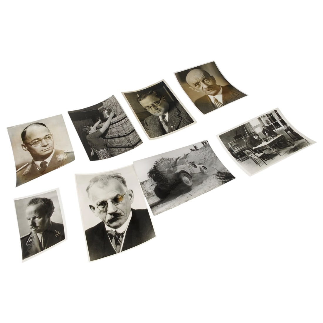 Set of WWII-Era German Press Photographs, Portraits and Scenes: A set of period press photographs including studio-style portraits of men in civilian dress and military uniform, a domestic interior scene of a woman at a tiled stove, an office interior with figures