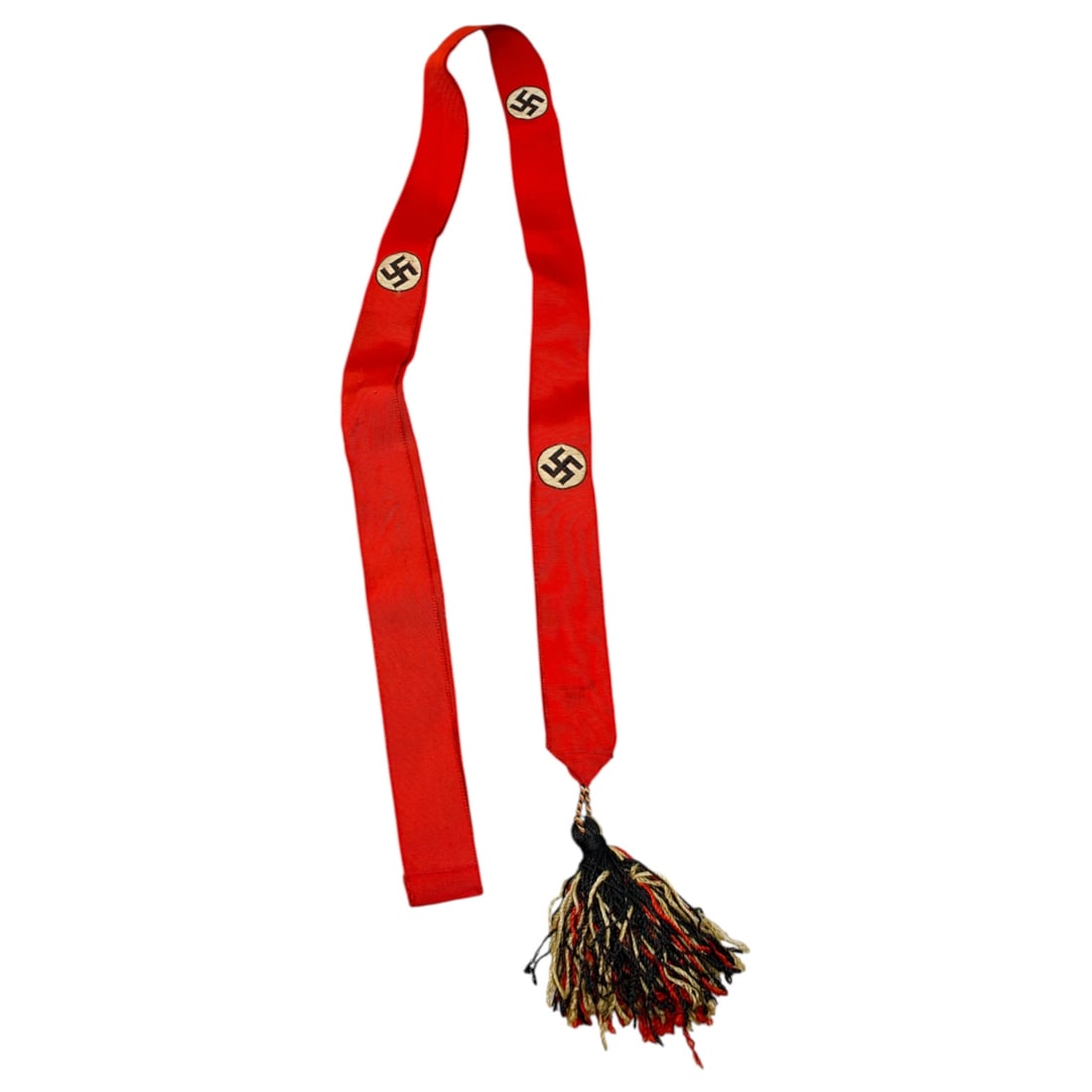 Third Reich Period Flag Standard Presentation Streamer with Tassel: A red ribbon streamer woven with repeating roundel emblems, each showing a black mobile cross motif on a light-colored ground, finished at one end with a multi-strand tassel in black, red, and tan thr