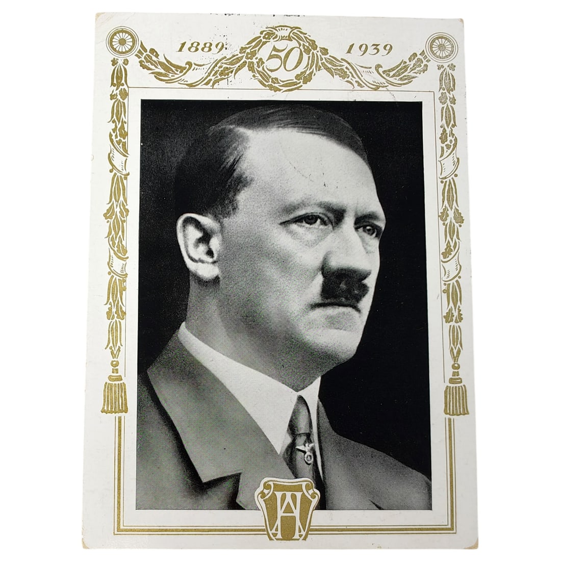Adolf Hitler Propaganda Postcard: A commemorative postcard marking the dates 1889-1939 and the number 50, featuring a right-facing portrait bust within a decorative gilt border with tasseled cord motifs and a monogram device at the ba