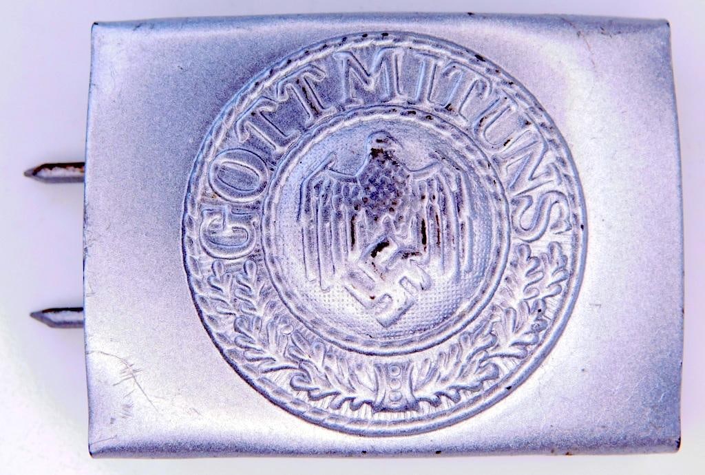 German WWII Army Enlisted Mans Belt Buckle: One piece die struck stamped steel construction. Front shows a German eagle clutching a swastika in his talons. It reads Gott Mit Uns (God With Us). Reverse side is maker marked GB. Includes the two p