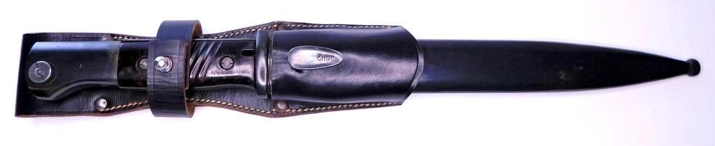 German WWII Mauser K-98 Combat Rifle Bayonet and Scabbard: The blued steel blade and scabbard are numbered and maker marked 6642 clc 43. Pair of brown bakelite handles. Includes the multi-piece machine sewn and riveted black leather belt frog. Reverse side is