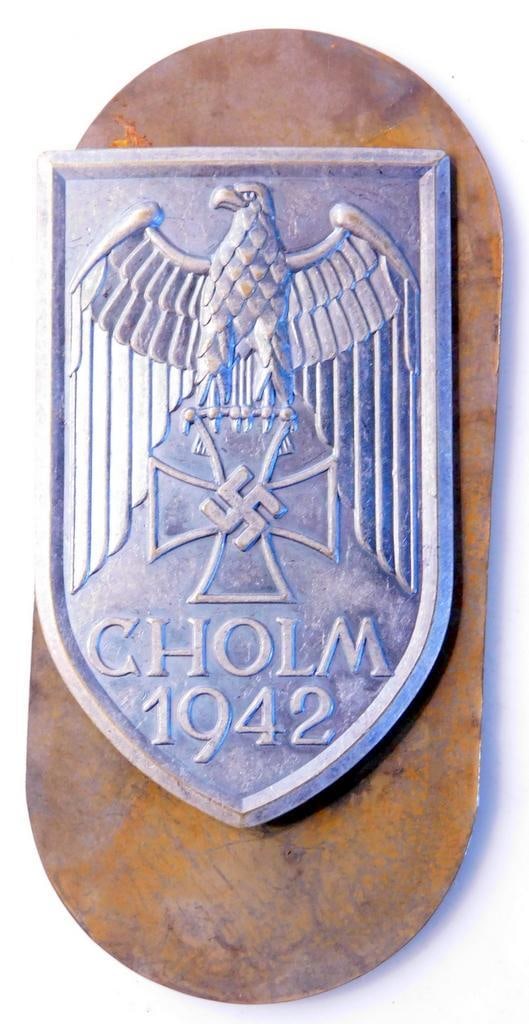 German WWII Army CHOLM 1942 Sleeve Shield: One piece die struck stamped nickel construction. Front shows an airplane in the center with a crossed pair of swords below. German eagle clutching an Iron Cross in his talons with swastika in the cen