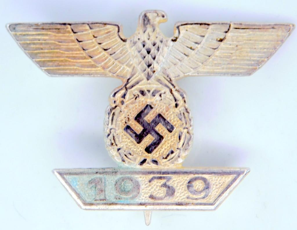 German WWII 1st Class Clasp to the Iron Cross: One piece die struck silver plated nickel construction. Front shows a German eagle clutching a swastika in his talons with a 1939 bar at the base. Wide vertical pin back with a c-catch. Awarded for re