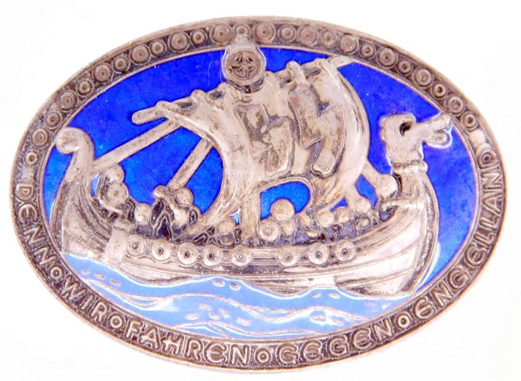 German World War II Waffen SS Victory In England Badge: One piece die struck vaulted nickel construction with enamel. Front shows a Viking ship with a pair of Waffen SS runics in the sail. It reads Denn - Fahren - Gegen - Eng 