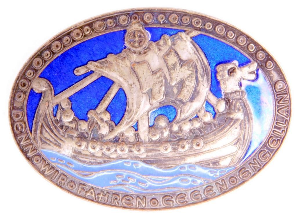 German World War II Waffen SS Victory In England Badge: One piece die struck vaulted nickel construction with enamel. Front shows a Viking ship with a pair of Waffen SS runics in the sail. It reads Denn - Fahren - Gegen - Eng 
