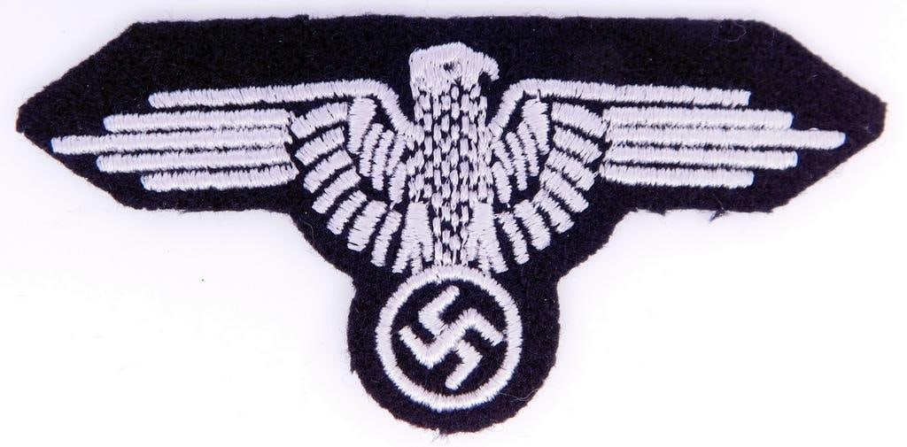 German WWII Waffen SS EM Arm Eagle: Machine embroidered in grey thread onto a black wool backing. Front shows a spread winged Waffen SS eagle clutching a swastika in his talons. This was to have been worn on the upper left sleeve of the