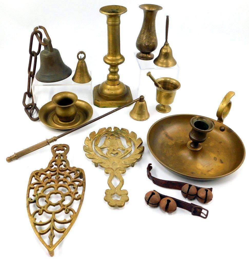 Collection of Brass and Metal Ware Candle Related Items: Assorted collection of brass and metalware items including candlesticks, small bells, candle snuffers, a decorative trivet, a wall hanger, and a pair of jingle bells on leather straps Items vary in si