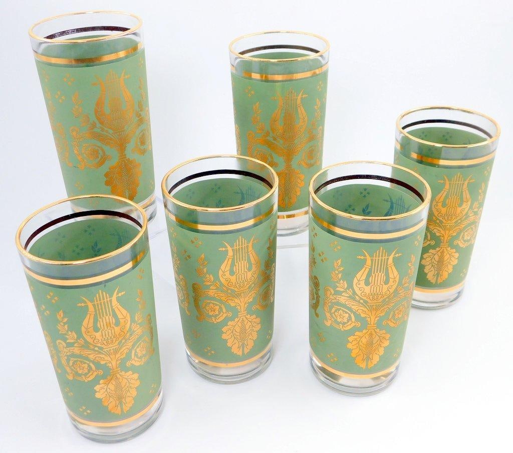 Jeanette Glass Co. Mid-Century Laurel & Lyre Glasses-Green Gold Harp, (6): Set of six highball glasses featuring a mid-century design of gold lyre and floral motifs on a green background Each glass is adorned with gold trim around the top edge The glasses are in good conditi