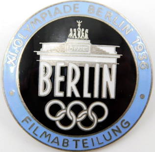 1936 Berlin Summer Olympics Film Maker Badge: Front reads XI. Olympiade Berlin 1936 Filmabteilung Berlin. Shows the Brandenburg Gate with the five Olympic rings in the center. Reverse is maker-marked Rob Neff Berlin W 57. Thin horizontal safety