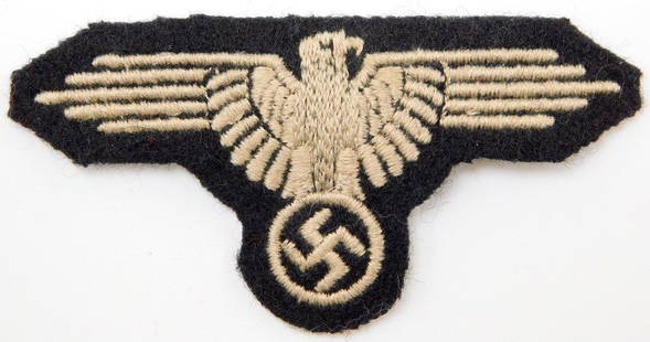 Waffen SS EM Arm Eagle: Front shows a spread-winged Waffen SS eagle clutching a swastika in his talons. Machine embroidered in gray cotton thread onto a black wool backing. For an enlisted man. Measures 3 1/4 inches