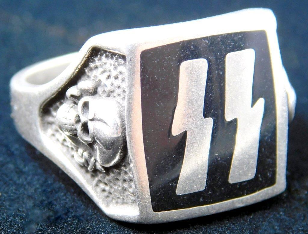 German WWII Waffen SS Officers Runic and Skull Ring: Front shows a pair of Waffen SS runics in the center flanked by a Waffen SS Totenkopf skull and cross bones on each side. Nickel construction with black enamel. Size 12 1/2.