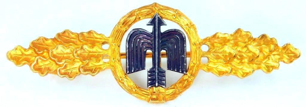 Luftwaffe Gold Fighter Flight Clasp: Front shows a winged arrow surrounded by a round oak leaf wreath and swastika at the base. All three are flanked by oak leaves on each side. Thin horizontal pin back with a c-catch. Two-piece brass an