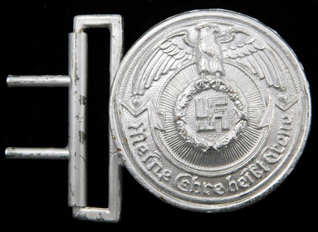 Waffen SS Officers Belt Buckle: Front shows a German eagle clutching a swastika in his talons. Reads Meine Ehre heist Treue (My Honor is Loyalty!). Includes the two prongs plus the belt hook on the back. Two-piece die-struck ni