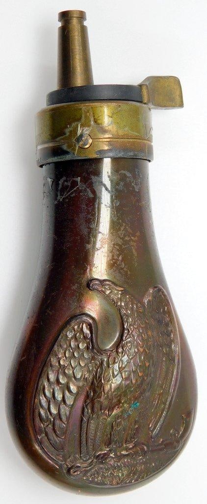 Old West COLT Pocket Model Pistol Gun Powder Flask: Front and the back show a spread-winged eagle perched on the barrel of a Colt pistol. Multi-piece stamped copper and brass construction. Measures 1 5/8 inches wide by 4 1/8 inches tall by 7/8 inches d