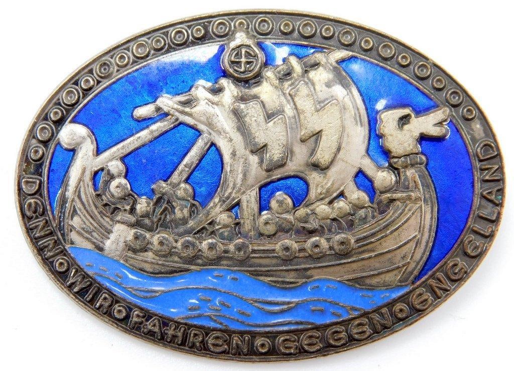 German World War II Waffen SS Victory In England Badge: Front shows a Viking ship with a pair of Waffen SS runics in the sail. It reads Denn Fahren Gegen Eng Elland. Reverse is maker-marked ges gesch. Thin horizontal safety pin back. One-piece die-struck v