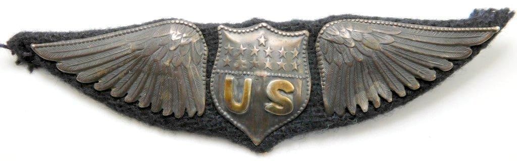 US WWI Aero Dallas Pilot Aviator Wing: Scarce. Six-piece die-struck silver and brass construction with a dark blue wool backing. Front shows a shield with the letters US in the center with 13 stars above. The shield is flanked by a wing on