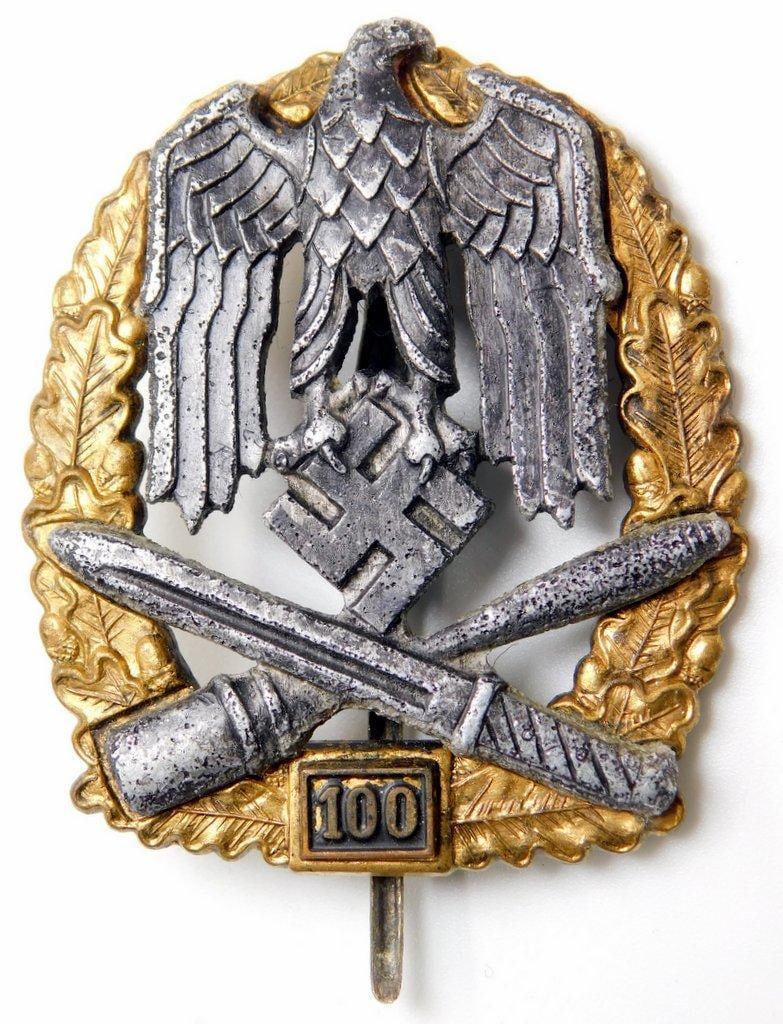 German WWII Army 100 General Assault Badge: Awarded for 100 combat encounters with the enemy. Three-piece four-domed rivet die-struck nickel and brass construction. Front shows a German eagle clutching a swastika in his talons in the center wit