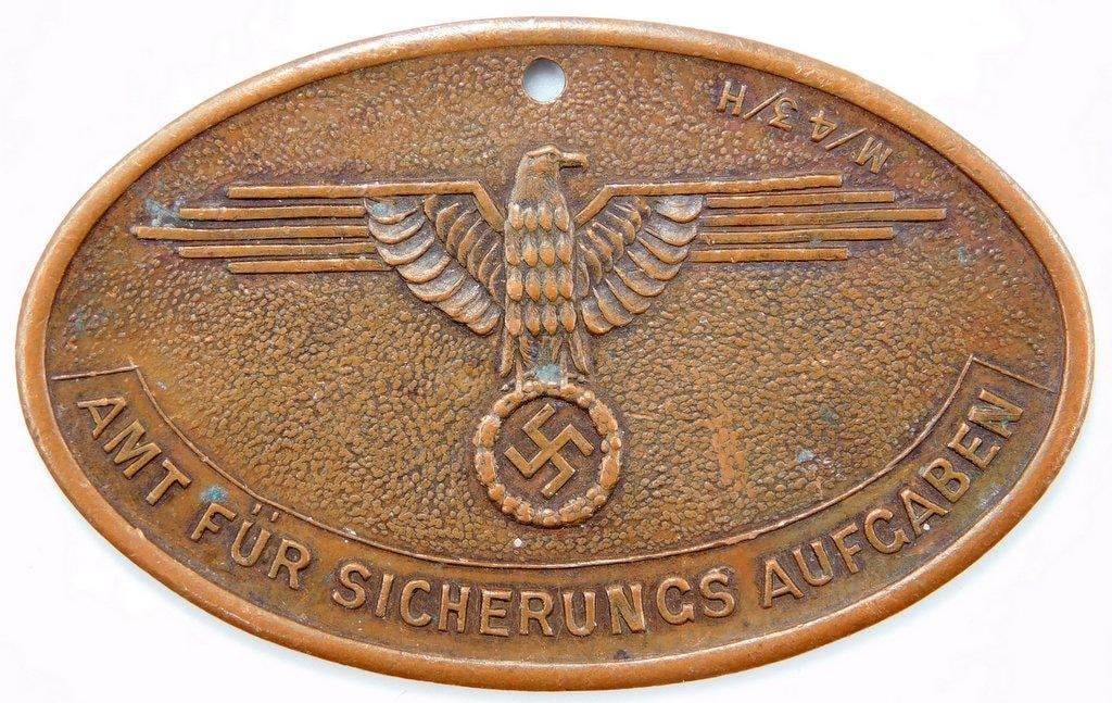 Waffen SS Criminal Danzig Identification Disc: One-piece die-struck copper construction. Front shows a Waffen SS eagle clutching a swastika in his talons in the center. Reads AMT FUR SICHERUNCS AUFGABEN M/14/H. Reverse reads SS HEIMWEHR DANZIG ARK