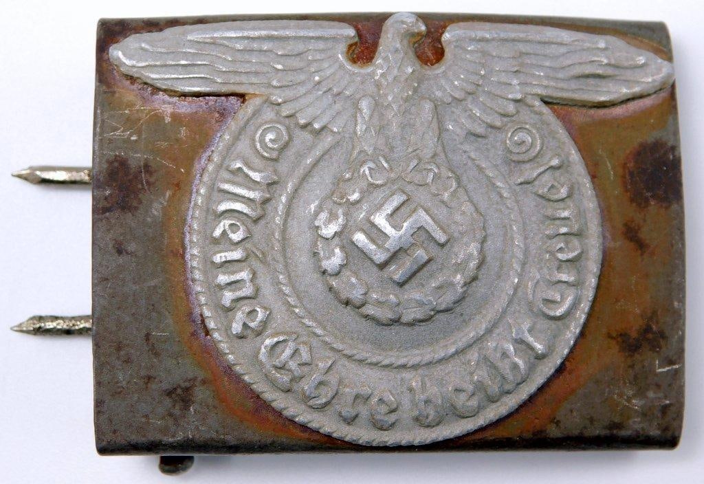 German WWII Waffen SS Schutz Staffel EM Belt Buckle: A scarce variation. Two-piece three-domed rivet die-struck steel and stamped nickel construction. Reverse is maker marked XX in a circle. Front shows a Waffen SS eagle clutching a swastika in his talo