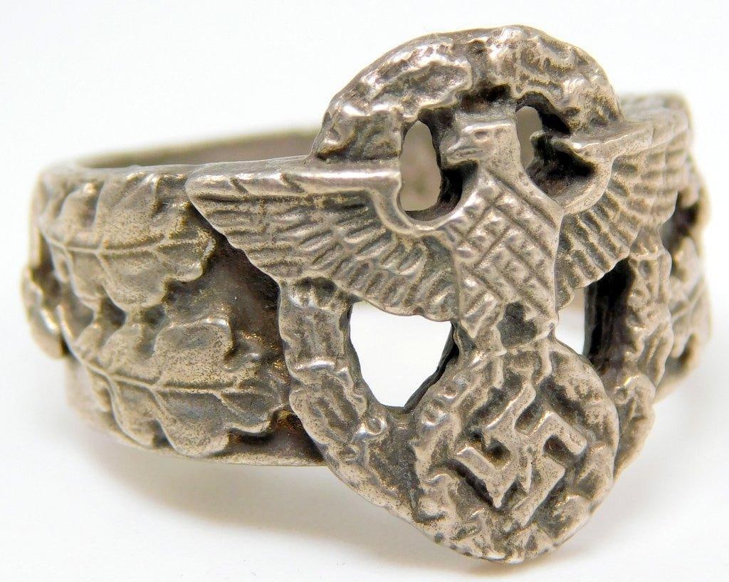 German WWII Police Officers Eagle Honor Ring: Silver construction with German writing on the inside. Oak leaves on each side of the ring. Front shows a police eagle clutching a swastika in his talons. Both are surrounded by an oval oak leaf wreat