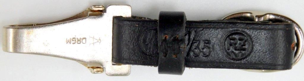 Waffen SS EM Dagger Hanger: Excellent condition. Black leather is maker-marked SS 1/35 RZM. Nickel belt clip is maker-marked A DRGM. For an enlisted mans dagger. Measures 5/8 inches wide 3 3/4 inches long.