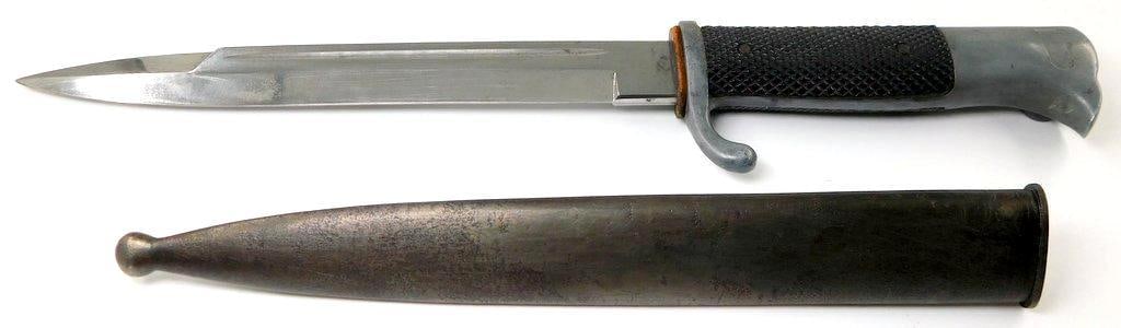 German Dress Bayonet and Scabbard, Short Model: Measures 13 7/8 inches long overall. Steel blade is maker-marked WKC with the Knight Head logo above. Measures 7/8 inches wide by 7 9/16 inches long. Steel scabbard measures 1 1/8 inches wide by 9 inc