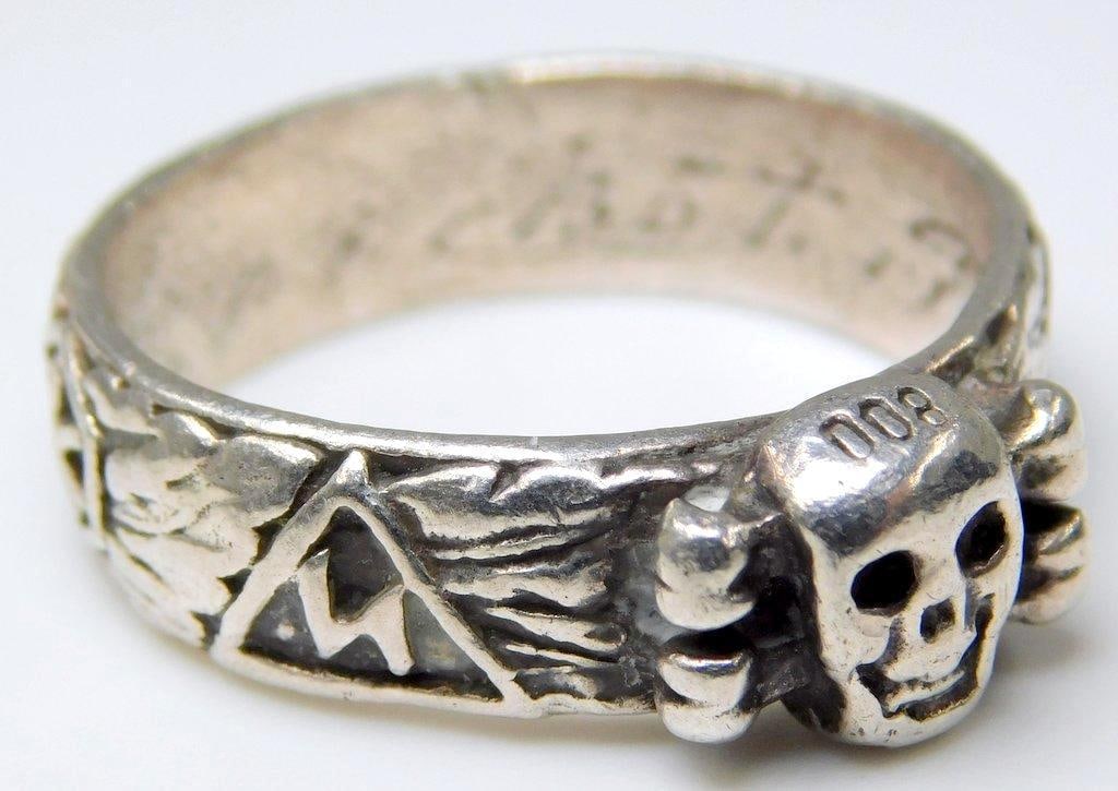 German WWII Waffen SS Officers Honor Skull Ring: Silver construction. Front shows a skull and cross bones with emblems around the outside. Size 10 1/2.