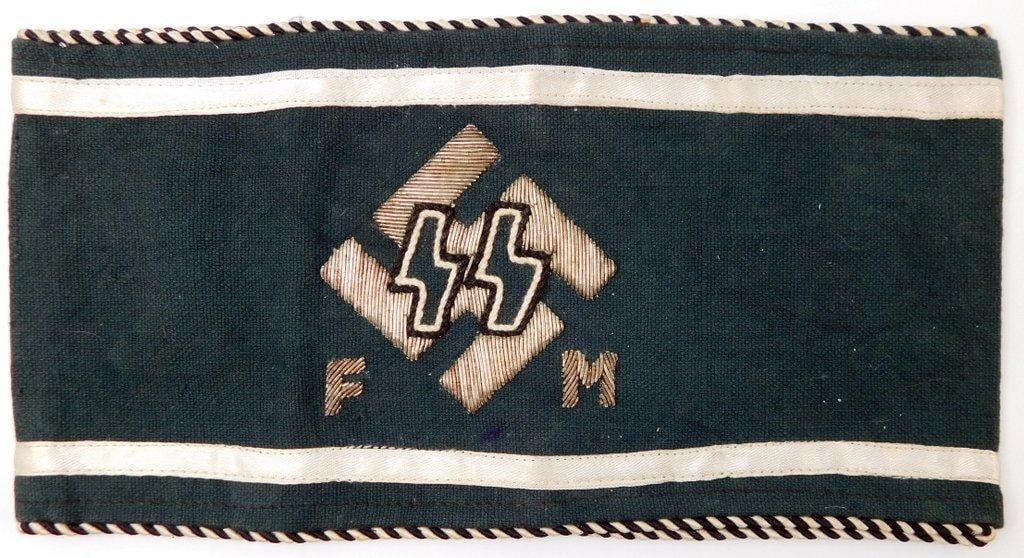 German WWII Waffen SS Officers FM Swastika Arm Band: Multi-piece hand-embroidered silver bullion wire machine-sewn onto multi-piece cotton with twisted black and white piping. Front shows a pair of SS runics with a raised silver bullion wire swastika in