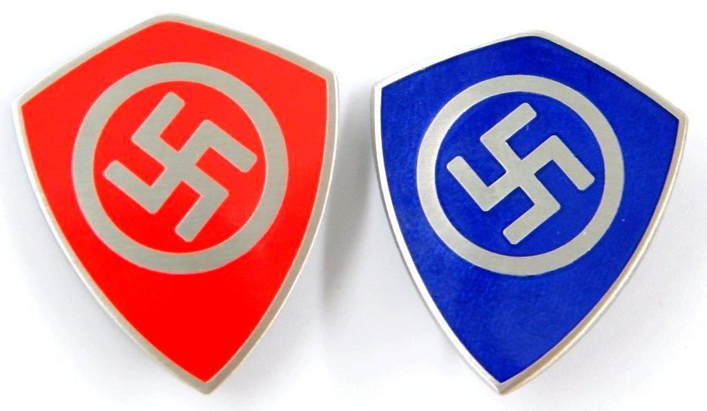 German WWII Swastika Shield Party Membership Badges, Two (2): Nickel construction with enamel. Front shows a swastika in the center of a shield. Reverse is maker-marked ges gesch. Thin vertical safety pin back. Measure 1 inch wide by 1 3/16 inches tall.
